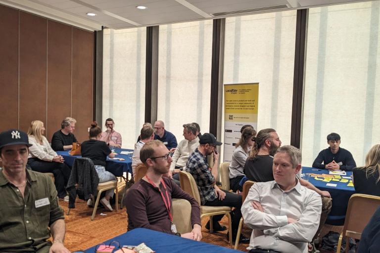 Attendees around tables discussing tech related issues